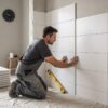 Tiler laying bathroom wall tiles during a renovation to show how long bathroom tiling takes